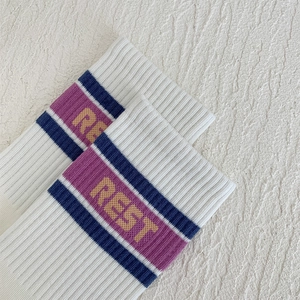 Detail view of cotton ribbed socks with purple stripes and REST lettering