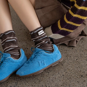 Detail of vintage striped knit socks with brand label paired with blue suede shoes