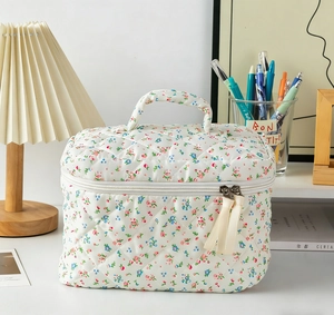Close-up of quilted floral cosmetic bag with sturdy handle and beige ribbon zipper detail