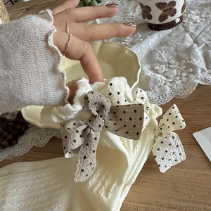 Nahaufnahme beiger Stricksocken mit schwarz gepunkteten Schleifen auf rustikalem Tisch