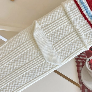 Detail of white ribbed knit socks featuring distinct red and blue striped cuffs