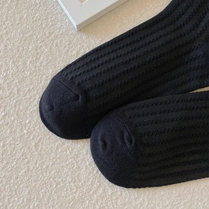Makro-Detailansicht schwarzer Rippstricksocken mit feiner Zehennaht auf Strukturstoff
