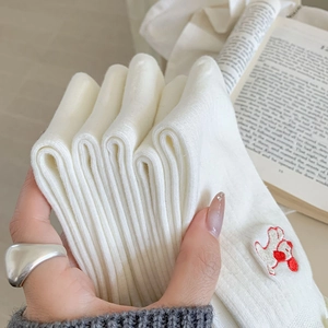 Détail de chaussettes en coton blanc avec broderie de chien et texture tricotée