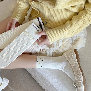 Detailed close-up of white Japanese knit socks with textured vertical stripes and floral trim