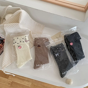 Detail of four pairs of sweet dot socks with embroidery in cream, brown, grey and black
