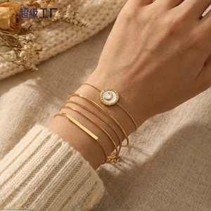 Detailed close-up of 5-piece gold bracelet set with moon disc on a model's wrist
