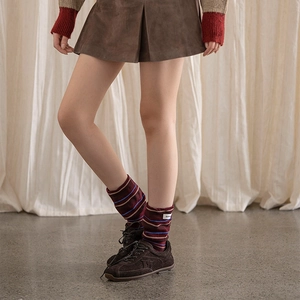 Detail of retro striped mid-calf socks with woven label paired with brown suede shoes