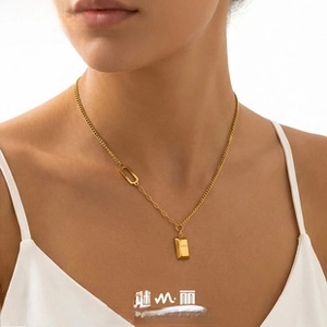 Detail of PVD gold plated Cuban link and paperclip chain necklace with gold bar pendant