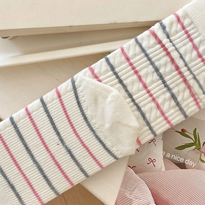 Detail of pink and grey striped cable knit socks with delicate bow lace texture