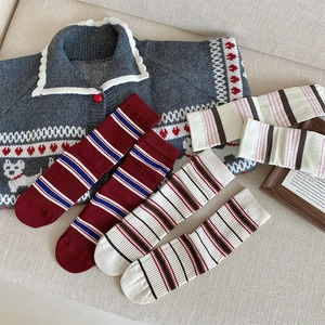 Detailed view of thick ribbed striped socks in red and cream on a warm winter knit background