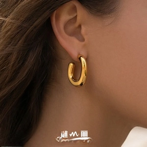 Macro close-up of a minimalist chunky gold hoop earring with polished metallic finish