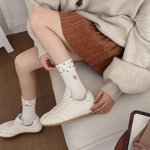 White knit crew socks with polka dot cuffs and strawberry embroidery worn with sneakers