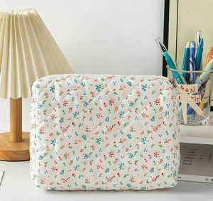 Quilted floral makeup bag detail with cream ribbon pull and metal zipper closure
