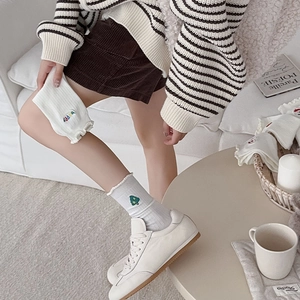 Gros plan de chaussettes en coton blanc avec broderie sapin de Noël et texte Happy