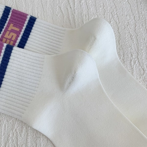 Detail of white cotton athletic socks with blue and purple stripes and EST lettering