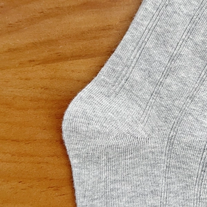 Macro view of light grey ribbed knit socks showing heel stitch detail and cotton texture