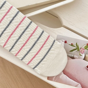 Close-up of cable knit socks with pink and grey stripes and textured cotton details