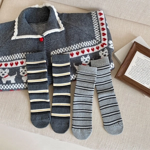 Flat lay of vintage striped socks and a knit cardigan with puppy pattern on beige cloth