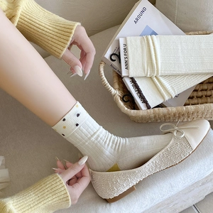 Close-up of white knitted crew socks with floral embroidery and ballet flat shoes