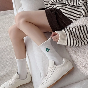 Détail de chaussettes en coton blanc avec broderie sapin de Noël et bordure en dentelle