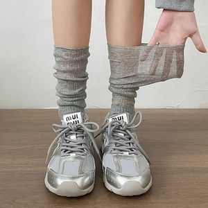 Vertical striped grey calf socks paired with metallic silver sneakers on wooden floor