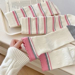 Detail of knit crew socks featuring pink and grey stripes with delicate ruffled edges
