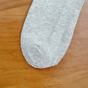 Macro detail of gray knitted mid-calf socks showing seamless toe and ribbed texture