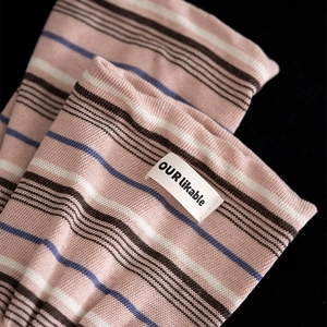Detail of striped knit socks with logo patch showing ribbed texture and pink color palette