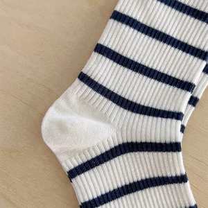 Gros plan sur la texture côtelée et le talon rayé bleu marine de la chaussette en coton