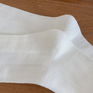 Nahaufnahme weißer gerippter Strickbaumwollsocken mit Fokus auf Stoffstruktur und Nähten