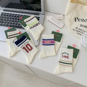 Detail of five-pack cream ribbed crew socks with colorful letter embroidery and tags