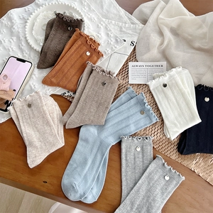 Close-up of ribbed texture and ruffled cuffs with silver button details on cotton socks