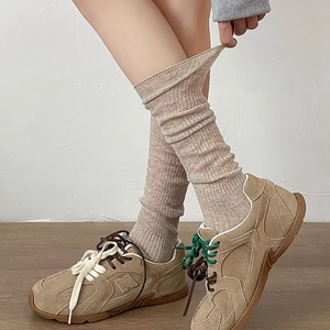 Close-up of beige ribbed knee-high socks showing elastic knit texture and stretch fit