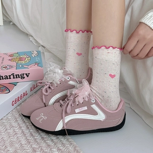 Detailed close-up of pink heart embroidery on beige crew socks with ruffle edges