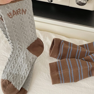 Close-up of thick knit cotton socks featuring brown stripes and BARN woven lettering