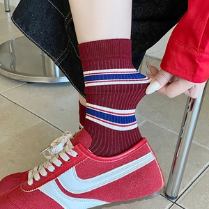 Detail of vintage burgundy ribbed socks with blue stripes paired with retro sneakers