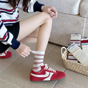 Detail of white cotton crew socks with red stripes and heart patterns with red sneakers