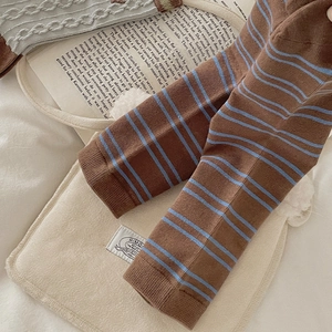 Detail of brown and blue striped knit fabric texture on cozy white faux fur background