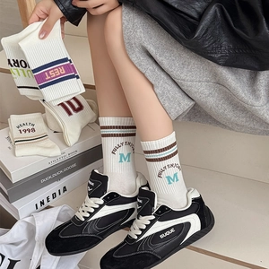Detailed macro view of cream-colored cotton mid-calf socks with rib cuffs and stripe patterns