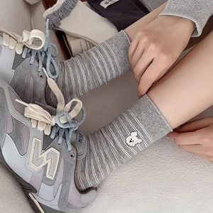 Gros plan sur des chaussettes rayées gris et blanc avec broderie de lapin mignon