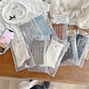 Detail of colorful ruffled cotton socks in branded matte packaging on wooden surface