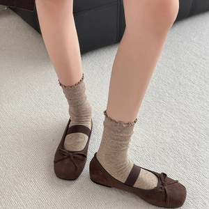Brown suede Mary Jane flats with bow detail and elastic strap worn with frilly socks