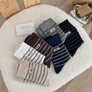 Detail of colorful striped cotton socks with Bee embroidery on a cozy soft surface