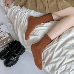 Detail of caramel ruffled crew socks with vintage button accents and ribbed texture
