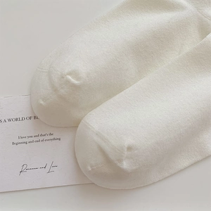 Close-up of white ribbed knit socks showing smooth toe stitching and fine fabric texture