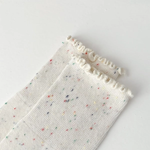 Detail of off-white knit socks with colorful confetti texture and ruffled wood ear edges