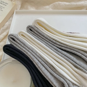 Close-up of ribbed cotton socks in black, grey and white with cozy lifestyle props