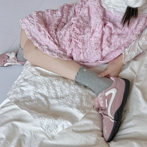 Pink low-top sneakers featuring silk bow laces and frilly grey crew socks on feet