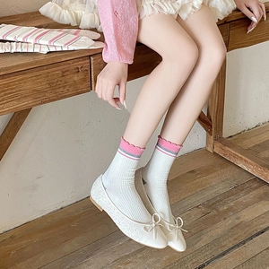 Detail of ballet flats with bow and striped crew socks with ruffled edges