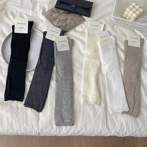 Close-up of ribbed cotton leg warmers in black, grey, beige and brown with brand tags